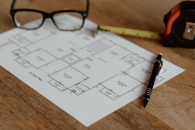 the blueprint of a home with a pen and tape measurer on top