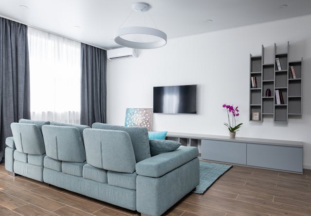 a living room with a light blue couch white walls and wooden flooring