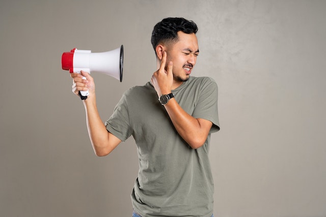 person blocking their ears from the sound of a megaphone