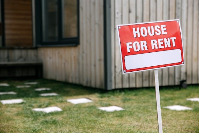 house with a for rent sign in front of it