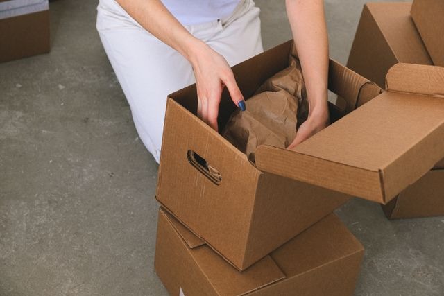 person placing objects in moving boxes