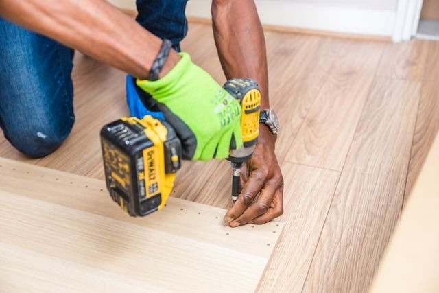 maintenance vendor using a drill on wood flooring