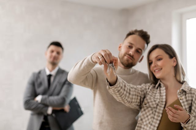 two people holding up keys as a man in a suit looks at them